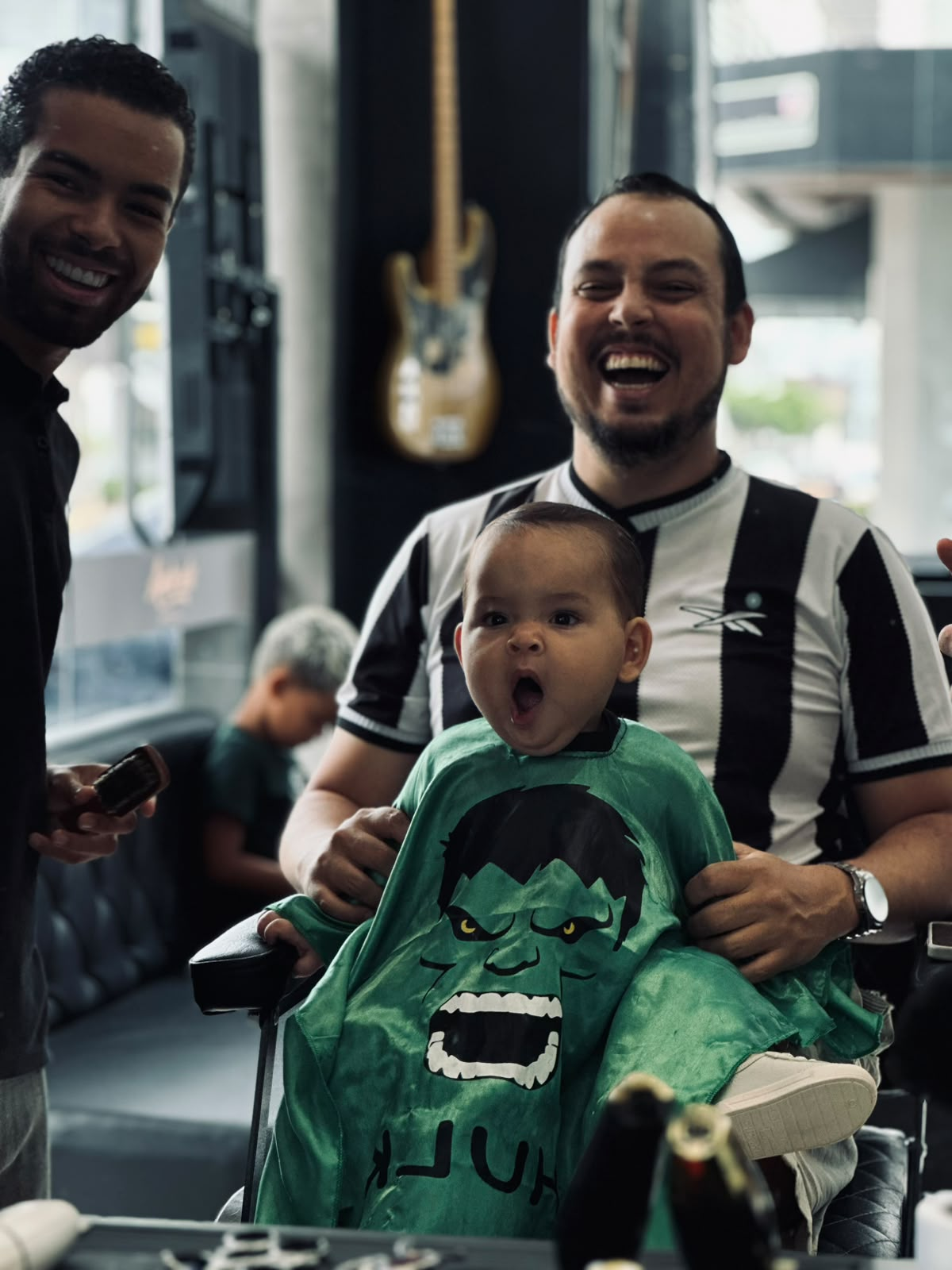 Cliente com filho na cadeira da barbearia Andrade